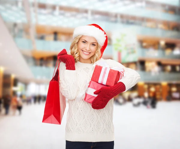 Sonriente joven en santa helper sombrero con regalos — Foto de Stock