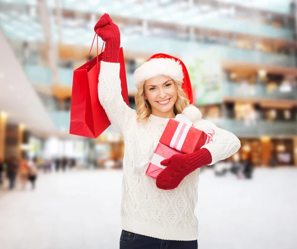 S úsměvem mladá žena v pomocníka čepice santa s dárky — Stock fotografie