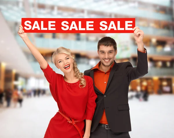 Smiling couple with red sale sign — Stock Photo, Image