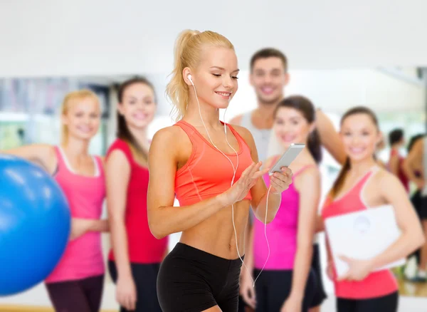 Mujer deportiva sonriente con teléfono inteligente y auriculares —  Fotos de Stock