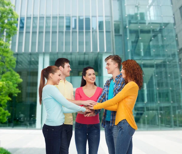 Smiling teenagers with hands on top of each other — Stock Photo, Image