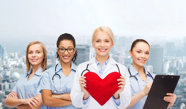 Doctora y enfermeras sonrientes con corazón rojo —  Fotos de Stock