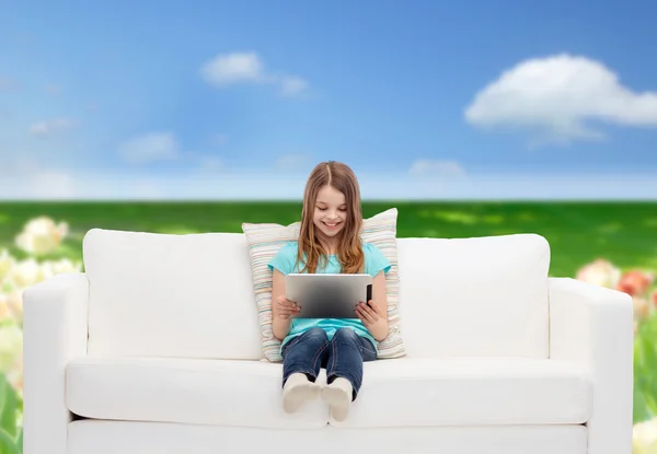 Little girl sitting on sofa with tablet pc — Stock Photo, Image