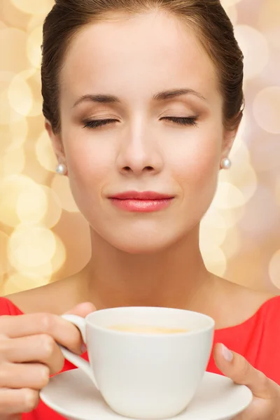 Lachende vrouw in rode jurk met kop koffie — Stockfoto