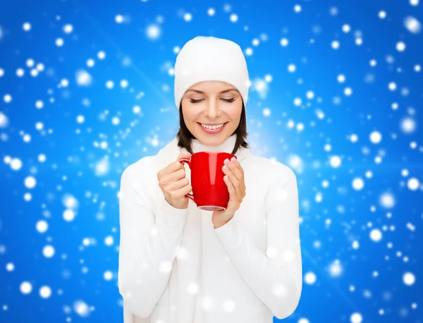 Jonge vrouw in winterkleren met kop glimlachend — Stockfoto