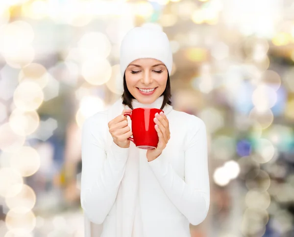 Улыбающаяся молодая женщина в зимней одежде с чашкой — стоковое фото