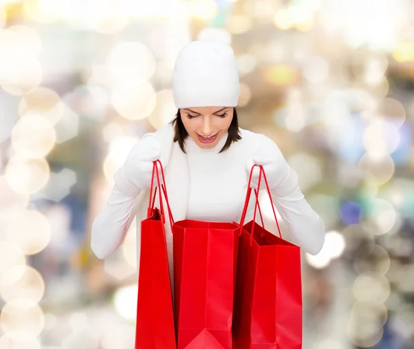 Smiling young woman with red shopping bags — Stock Photo, Image