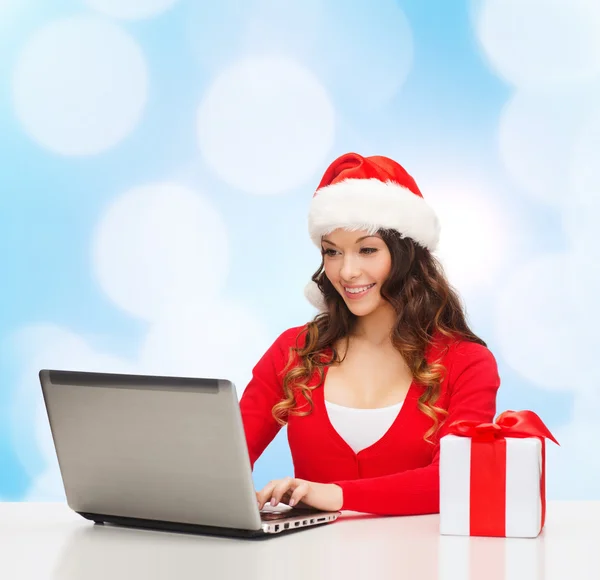 Mulher sorridente com caixa de presente e laptop — Fotografia de Stock