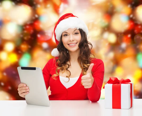 Donna sorridente in cappello di Babbo Natale con regalo e tablet pc — Foto Stock