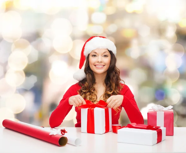 Sorrindo mulher em santa helper chapéu embalagem presentes — Fotografia de Stock