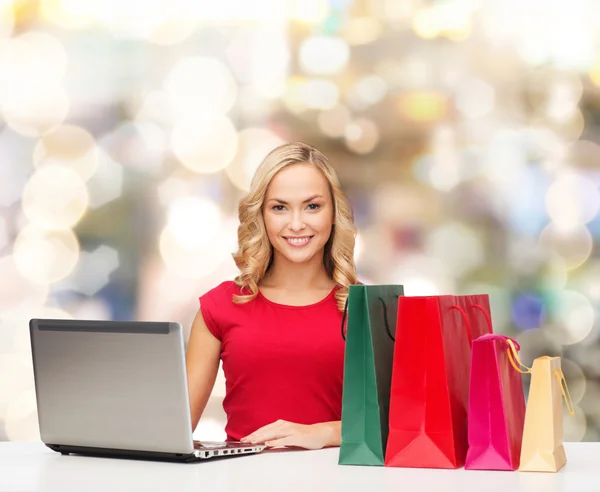 Mujer sonriente en camisa roja con regalos y portátil — Foto de Stock