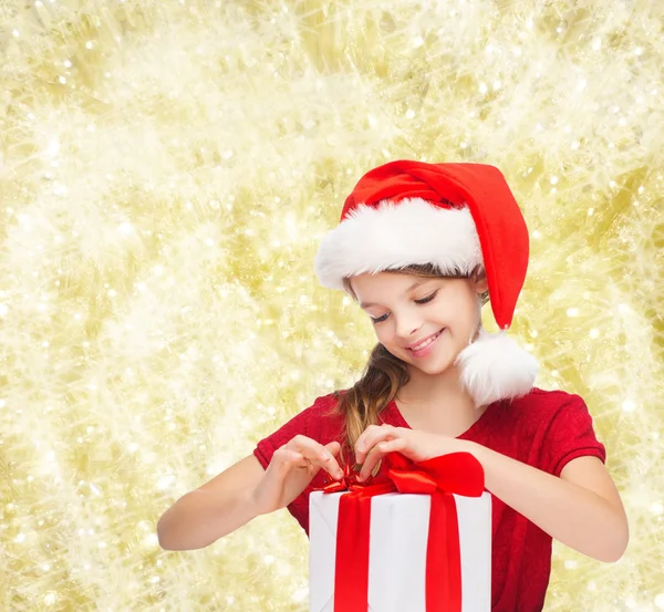 Chica sonriente en sombrero de ayudante de santa con caja de regalo —  Fotos de Stock