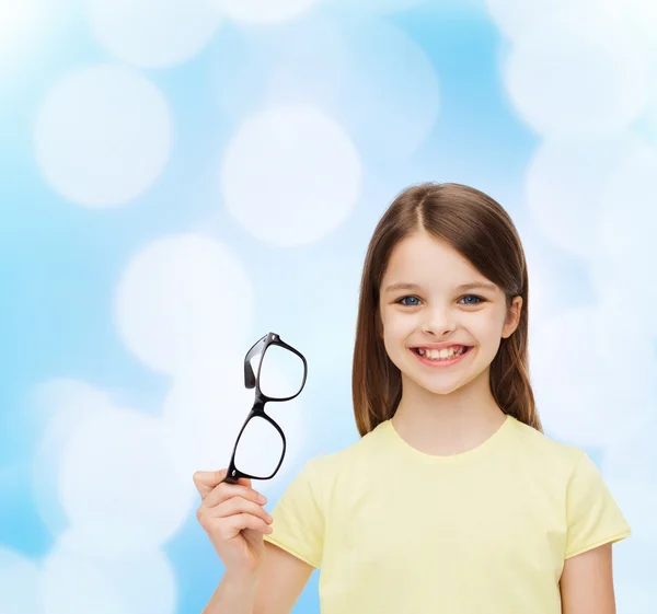 Smiling cute little girl holding black eyeglasses — Stock Photo, Image