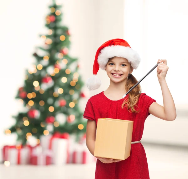 Chica sonriente en sombrero de ayudante de santa con caja de regalo — Foto de Stock