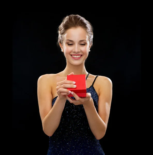 Mujer sonriente sosteniendo caja de regalo roja — Foto de Stock