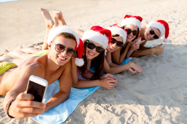 Gruppe von Freunden in Weihnachtsmützen mit Smartphone — Stockfoto