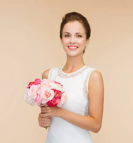 Mulher sorridente em vestido branco com buquê de rosas — Fotografia de Stock