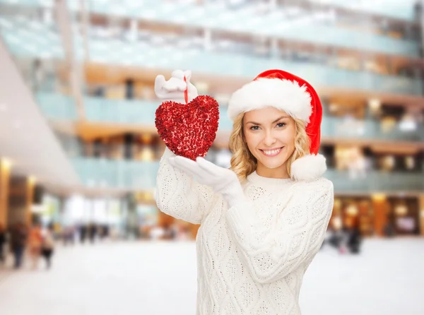 Usmívající se žena v santa hat pomocníka s červeným srdcem — Stock fotografie