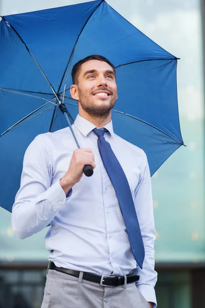 Joven hombre de negocios sonriente con paraguas al aire libre — Foto de Stock