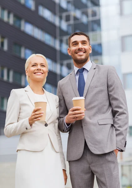 Hombres de negocios sonrientes con vasos de papel al aire libre — Foto de Stock