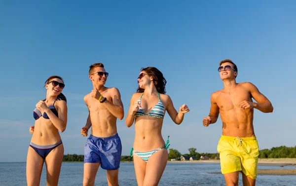 Lachende vrienden in zonnebril uitgevoerd op strand — Stockfoto