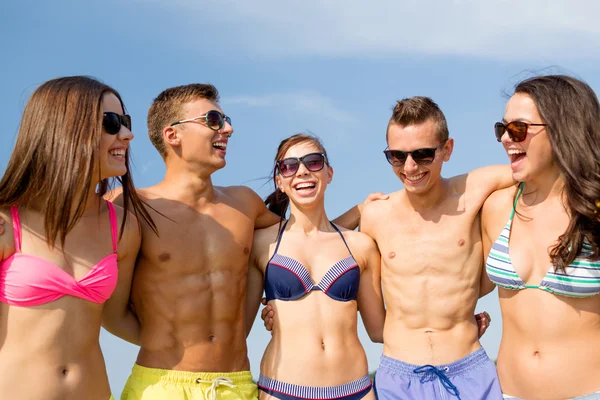 Улыбающиеся друзья в солнечных очках на летнем пляже — стоковое фото