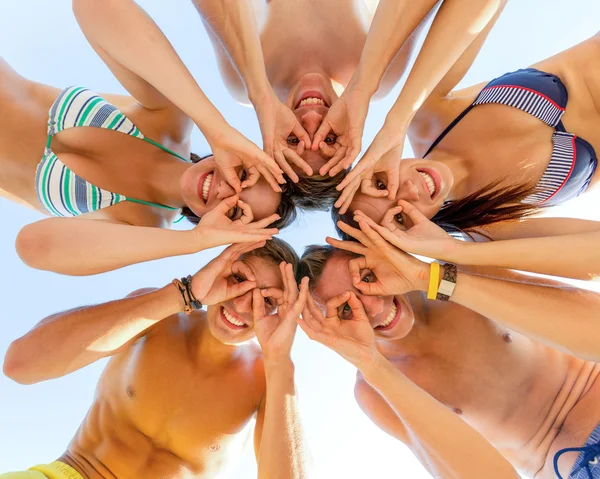 Lächelnde Freunde im Kreis am Sommerstrand — Stockfoto