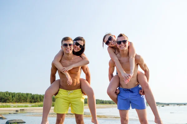 Amigos sonrientes en gafas de sol en la playa de verano — Foto de Stock