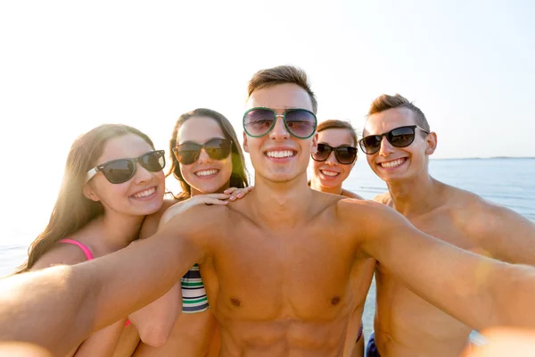 Группа улыбающихся друзей, делающих селфи на пляже — стоковое фото