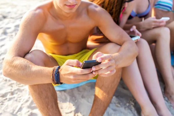 Närbild av vänner med smartphones på stranden — Stockfoto