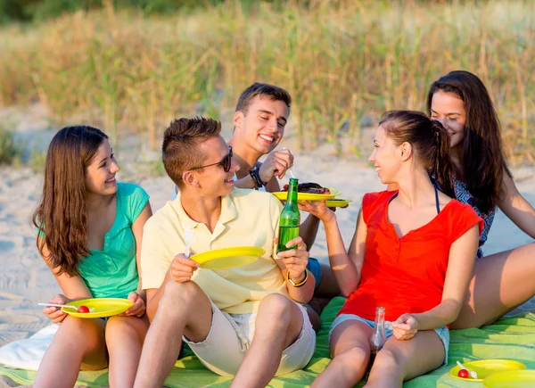 Amigos sonrientes sentados en la playa de verano — Foto de Stock