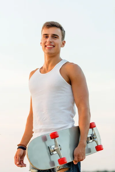 Smiling teenage boy with skateboard outdoors — Stock Photo, Image