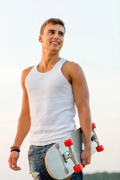 Усміхнений хлопчик-підліток зі скейтбордом на відкритому повітрі — стокове фото
