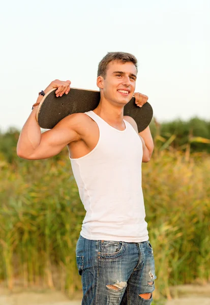 Smiling teenage boy with skateboard outdoors — Stock Photo, Image