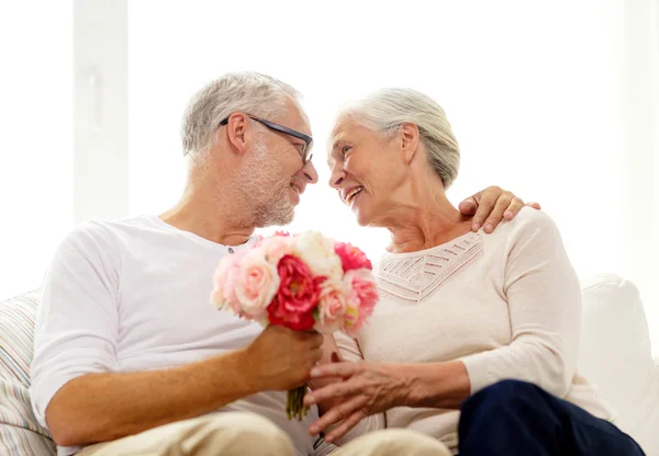 Glückliches Seniorenpaar mit Blumenstrauß zu Hause — Stockfoto