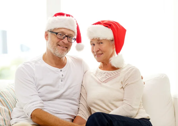 Feliz pareja de ancianos en santa helper sombreros en casa — Foto de Stock