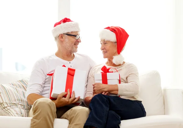 Feliz pareja de ancianos en sombreros de santa con cajas de regalo —  Fotos de Stock