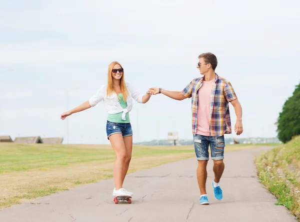 Usmívající se pár s skateboard venku — Stock fotografie