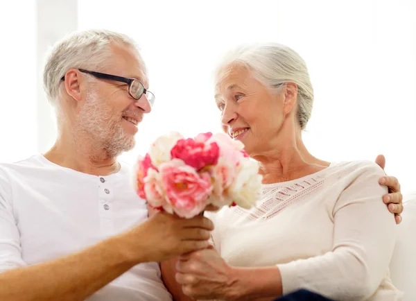 Feliz pareja de ancianos con ramo de flores en casa — Foto de Stock