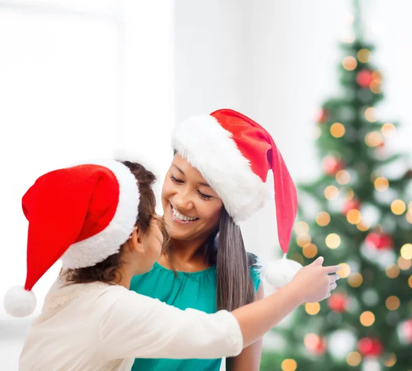 Hugging mother and daughter in santa helper hats — Stock Photo, Image