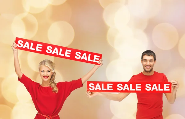 Smiling man and woman with red sale signs — Stock Photo, Image