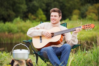 smiling man with guitar and dixie in camping clipart