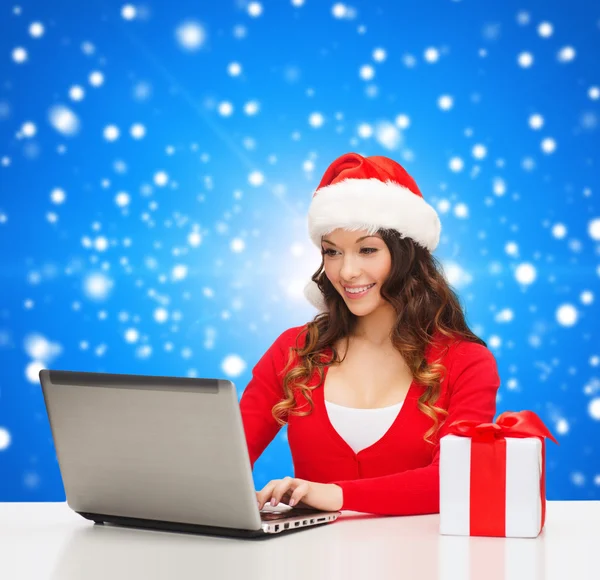 Mulher sorridente com caixa de presente e laptop — Fotografia de Stock