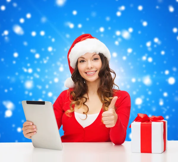 Lachende vrouw in kerstmuts met een geschenk en tablet pc — Stockfoto