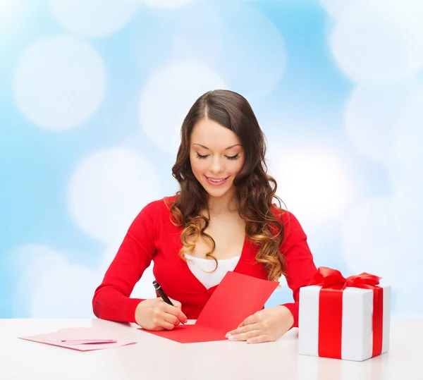Mulher sorrindo com caixa de presente escrevendo carta — Fotografia de Stock