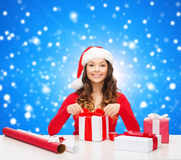 Usmívající se žena v santa hat pomocníka na balení dárků — Stock fotografie