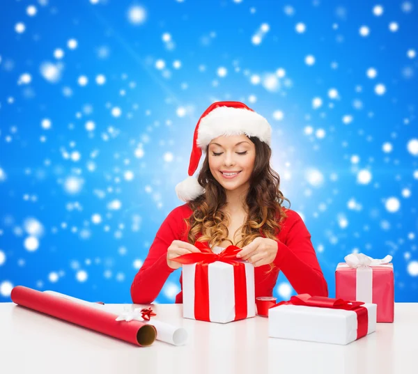 Sorrindo mulher em santa helper chapéu embalagem presentes — Fotografia de Stock