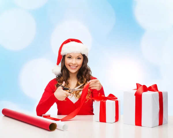 Lächelnde Frau mit Weihnachtsmann-Helferhut beim Packen von Geschenkkarton — Stockfoto