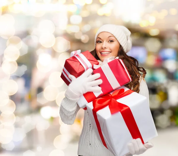 Glimlachend jonge vrouw in helper kerstmuts met geschenken — Stockfoto