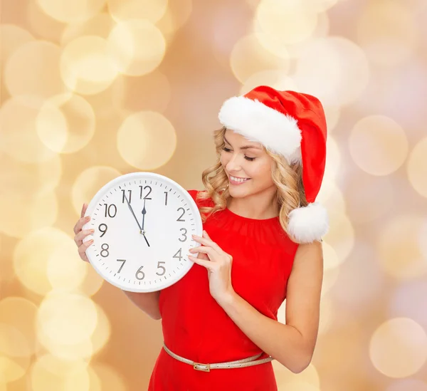 Femme souriante dans santa chapeau d'aide avec horloge — Photo